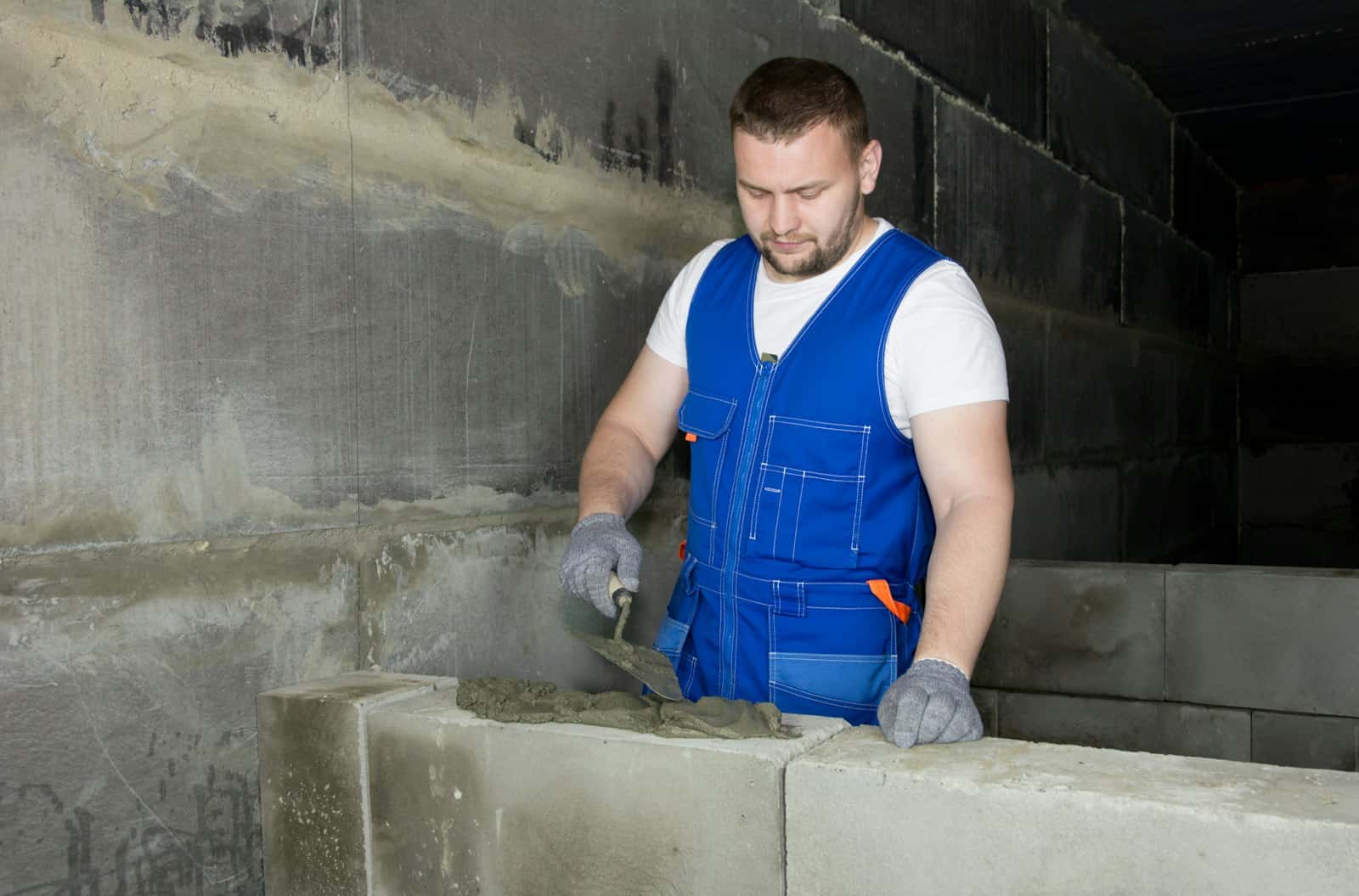 Mason repairing a concrete block foundation wall