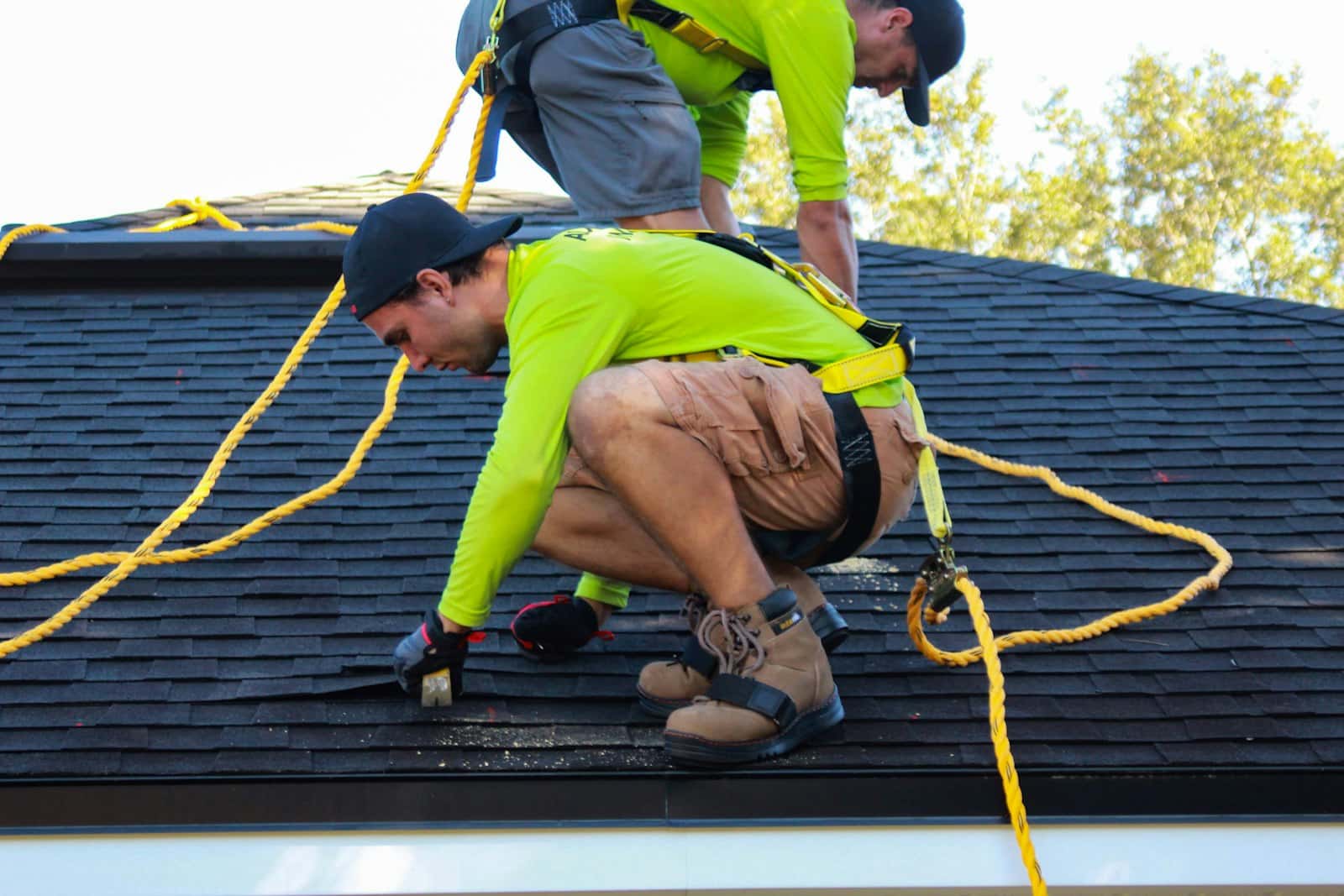 Roofer repairing asphalt shingles on a residential roof